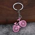 Pink bicycle keychain with alloy link chain and rhinestone accents on wood background - Pink