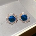 Macro shot of blue zircon starburst stud earrings set in a grey jewelry gift box - Gold-Blue