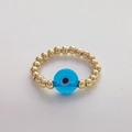 Macrobeeld van gouden kralen en blauw Evil Eye-bedeltje op een handgemaakte ring - Maat 7 (Elastisch) / Blauw