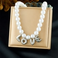 Close-up of pearl necklace with silver LOVE letter pendants on a beige jewelry box lid - Silver LOVE Letter Style (N3743)