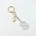 Close-up of golden keychain with letter S rhinestone charm and engraved heart pendant - Letter S