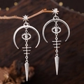 Makro-Detail gotischer Silbermond-Ohrringe mit Teufelsauge und Speer-Anhänger am Ast - Silber Stil