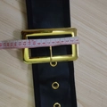 Black Santa Claus belt with a large gold buckle and metal eyelets on a wood table - Oversized Belt