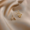 Elegant gold X-shaped cross earrings with sparkling zircon stones on champagne silk - Gold