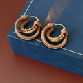 Detail of minimalist double-layered round hoop earrings on a blue textured jewelry box - Coffee (Real Gold Plated)