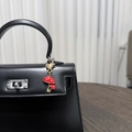 Détail d'un porte-clés champignon en émail rouge sur un sac à main en cuir noir - Double Champignon