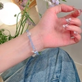 Detail of light blue crystal beaded bracelet with iridescent bow pendants on wrist - Blue-Star Moon