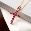 Macro shot of gold-plated geometric cross pendant with inlaid red square gemstones - Red