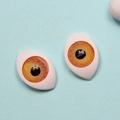 Detailed macro view of 12x16mm orange acrylic doll eyes with intricate iris texture - Yellow Bloodshot