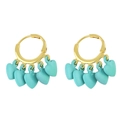 Gros plan de boucles d'oreilles créoles dorées avec plusieurs pendentifs cœur turquoise - Vert clair