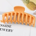 Close-up of large orange plastic hair claw clip with hollowed-out dragon bone structure - Matte Yellow