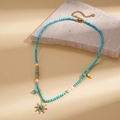 Gros plan sur collier de perles et turquoise avec pendentif soleil et bijoux dorés - Soleil Bleu