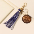 Blue tassel keychain with wood MAMA charm and gold hardware on beige background - Pentagram