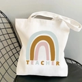White canvas tote bag featuring a colorful rainbow and Teacher print on a black mesh chair - STD374-L Colorful Line Rainbow/TEACHER