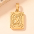 Macro detail of gold rectangle pendant featuring embossed letter X with textured patterns - Letter X
