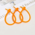 Three orange silicone cable ties in a looped lock state on a modern white background - Bright Orange