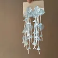 Close-up of light blue flower tassel earrings with layered translucent petals and beads - 22# Silver Needle - Light Blue
