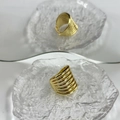 Close-up detail of 18k gold plated multi-layer spiral ring on textured glass - Clear