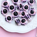 Macro detail of eye-shaped resin beads with pink and purple floral edges on white ceramic - Black Bead Pink Purple Cream White Flower