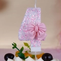 Pink glitter number 4 birthday candle with cute bow decoration on a cream cake - Number 4