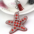 Detail of red starfish keychain with sparkling rhinestones, tassel, and silver bell charm - Red