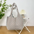 Detail of blue and beige wave pattern knit tote bag showing woven texture on a white chair - Vertical Stripe Khaki