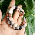 Bracelet tressé en pierre de lave et perles de marbre rose sur fond de plantes vertes - Cordon de serrage réglable / Corde tressée grise double rangée