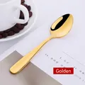 Cucchiaino da caffè dorato in acciaio inossidabile lucido su sfondo di libro - Regolare 14cm / Oro