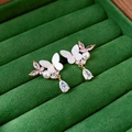 Detalle de aretes de mariposa dorados con circonitas rosas y gotas en terciopelo verde - Pin de Plata - Pendientes de Gota de Mariposa