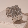 Macro shot of silver wide cuff bracelet with irregular lava texture on stone slab - Silver
