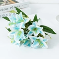 Bouquet de lys artificiels blancs aux pointes bleues avec feuilles vertes sur table - Bleu
