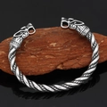 Brazalete vikingo plateado con cabezas de dragón y diseño trenzado sobre madera - Color Acero