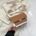 Braune und weiße Umhängetasche mit geometrischem Gurt und Goldbeschlägen auf beigem Blazer - Khaki
