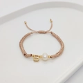 Detail of woven bracelet with letter B bead and freshwater pearl on white ceramic tray - Letter B