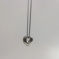 Detailopname van een gepolijste zilveren hart hanger aan een dun zwart koord ketting - Zilver Hol Hart (Koord)
