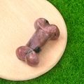 Pink and purple natural crystal bone carving with black veins on wooden tray - Rhodonite