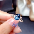 Elegant silver ring featuring an oval blue gemstone and small side diamonds on a finger - Platinum Ljz-268 / Adjustable Open