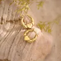 Detail view of 18K gold Claddagh hoop earrings with heart and crown on rustic wood - Vintage Claddagh Heart (EH283)