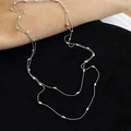 Gros plan d'un collier en perles argentées avec grains de riz métalliques sur velours noir - Argenté