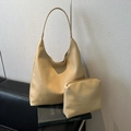 Beige litchi grain hobo bucket bag with matching zipper pouch on a black book - Litchi Pattern Khaki