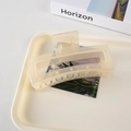 Detail einer großen matt cremegelben rechteckigen Haarklammer auf einem Tablett - Cremeweiß