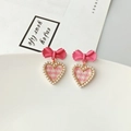 Detailed close-up of bow earrings featuring pink checkered hearts and pearl beads - Pink Plaid