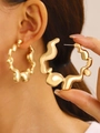Polished gold irregular molten lava hoop earring worn by a model in a lifestyle shot - Gold Large Lava Hoop