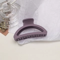 Detail view of a matte purple semi-circular shark hair claw clip on white crinkle paper - Semi-circle / Purple