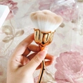 Rose-shaped makeup brush with golden handle and gradient soft bristles held in hand - Gold Handle Brown & White Bristles