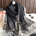 Détail d'une écharpe en soie noire aux motifs dorés posée sur une chemise blanche - Noir avec Motif Doré