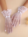Dettaglio guanti da sposa in pizzo bianco con fiocchi di raso e strass lucenti - Bianco