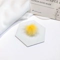 Detail of a soft yellow mink fur pompom placed on a white marble hexagon coaster - Yellow