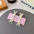 Set of two matte pale yellow X-shaped hair clips for women on a pink display card - Off-White Cross (Pair)