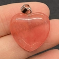 Peach pink heart-shaped natural stone pendant with silver clasp held by hand - 20mm / Watermelon Quartz